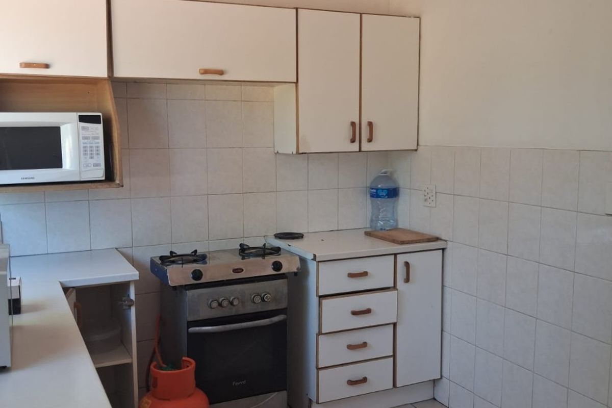 A functional kitchen featuring white cabinetry, tiled backsplash, tiled flooring, and a built-in gas stove setup.