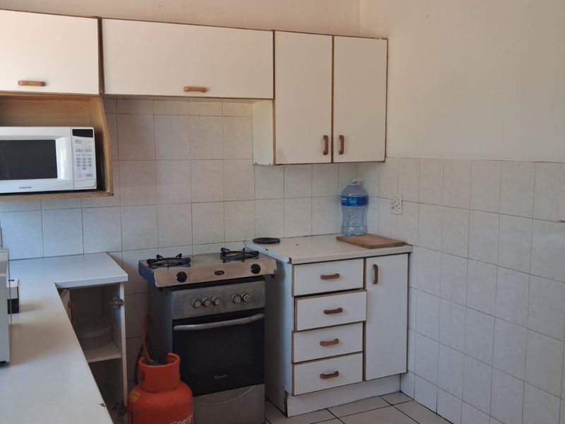A functional kitchen featuring white cabinetry, tiled backsplash, tiled flooring, and a built-in gas stove setup.