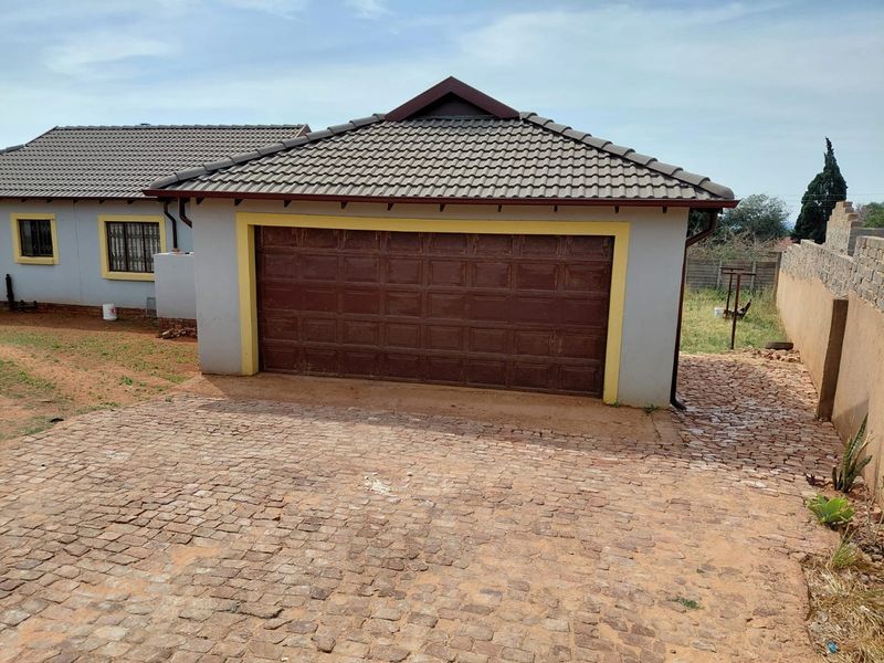 A detached single garage featuring a tiled roof and a brown sectional door, set on a cobblestone driveway.