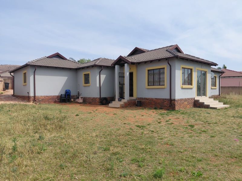 Rear view of a single-story house featuring a tiled roof, brick base detailing, and a sliding glass door leading to the yard.