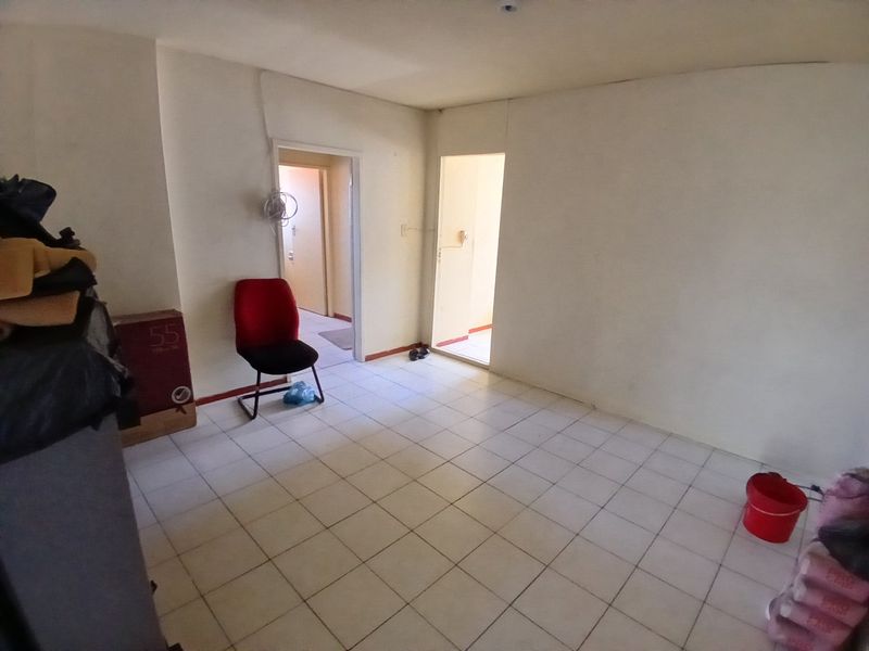An empty living area featuring tiled flooring and neutral walls, providing a blank canvas for potential interior design and renovation.