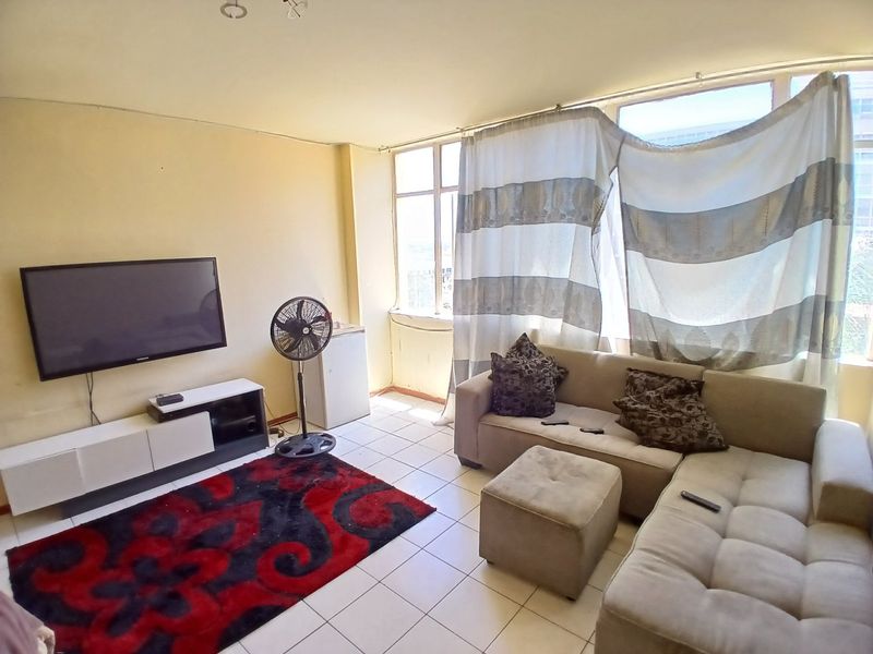 A living room featuring tiled flooring and large windows that provide natural light, offering a blank canvas for potential interior updates.