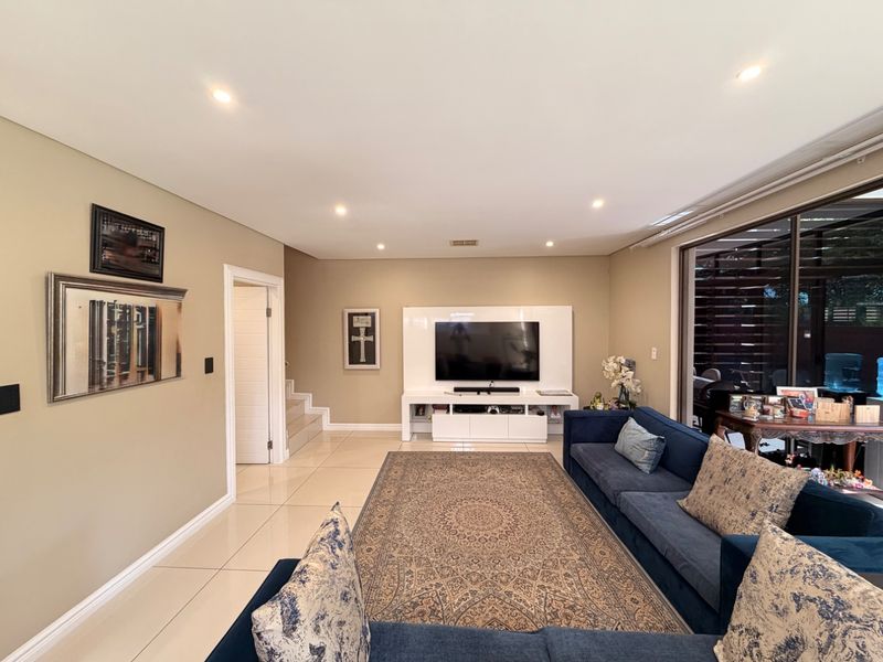 Spacious living room featuring polished porcelain floor tiles, recessed downlighting, and large sliding glass doors that provide ample natural light.