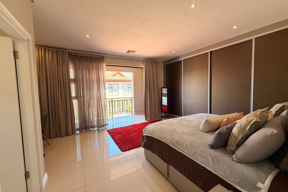 Spacious bedroom featuring large built-in cupboards, polished tile flooring, recessed lighting, and direct access to a private balcony through sliding glass doors.
