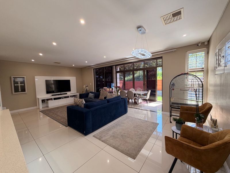 Spacious open-plan living and dining area featuring polished tiled floors, recessed lighting, and large sliding glass doors providing seamless access to the outdoor space.