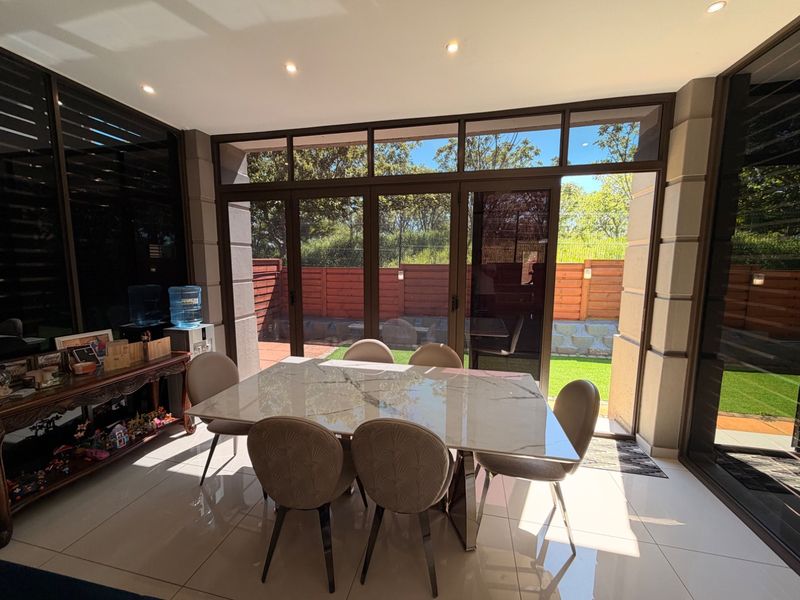 A bright, enclosed patio area featuring large aluminium-framed glass stacker doors that open out to a private garden space.