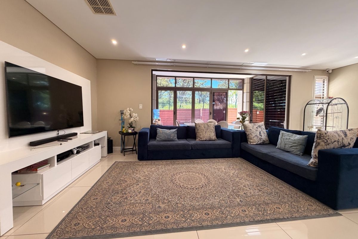Spacious living room featuring tiled flooring, recessed downlighting, and large sliding glass doors providing natural light and access to the outdoor area.