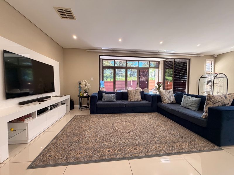 Spacious living room featuring tiled flooring, recessed downlighting, and large sliding glass doors providing natural light and access to the outdoor area.