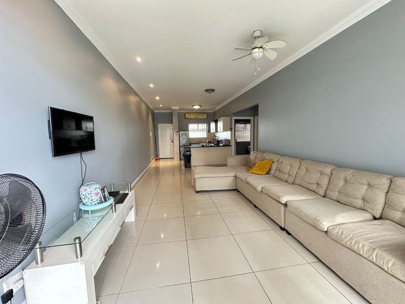 Spacious open-plan living area featuring tiled flooring, recessed lighting, and a seamless flow into the kitchen space.