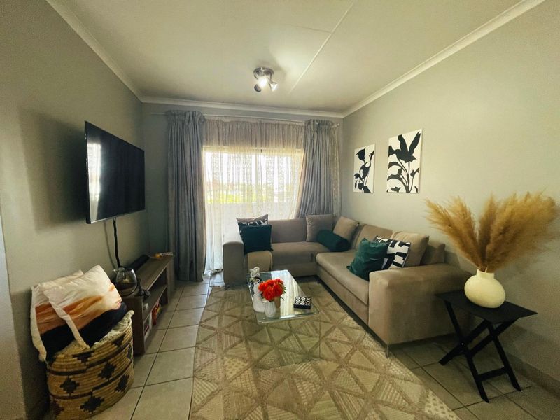 A comfortable living room featuring tiled flooring, neutral wall tones, and a sliding glass door that provides natural light and access to the exterior.