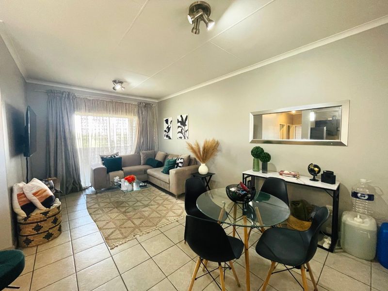 An open-plan living and dining area featuring tiled flooring, neutral wall finishes, and a sliding glass door providing natural light.