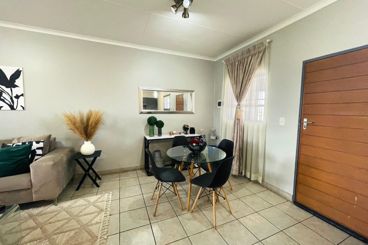 A well-maintained living area featuring neutral tiled flooring, a modern ceiling light fixture, and a solid horizontal panel entrance door.