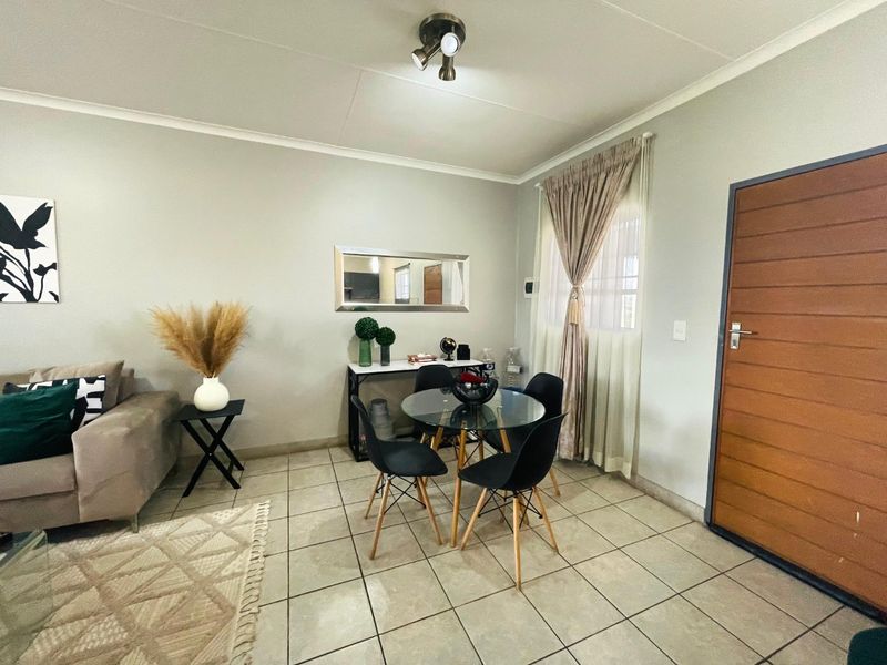 A well-maintained living area featuring neutral tiled flooring, a modern ceiling light fixture, and a solid horizontal panel entrance door.