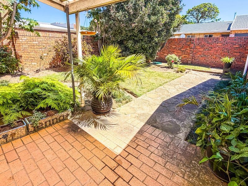 A private rear garden featuring a paved patio area, stone pathway, and brick boundary walls, offering a functional outdoor space for relaxation.