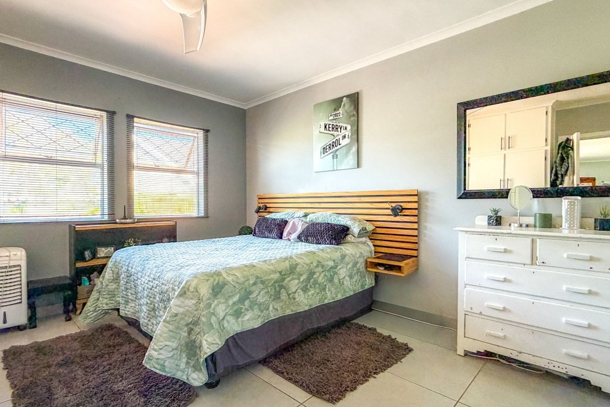 A well-lit bedroom featuring tiled flooring, a ceiling fan, and a custom built-in wooden headboard with integrated lighting.