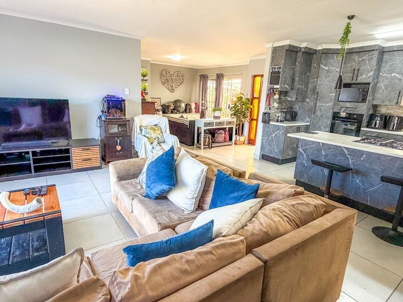 Spacious open-plan living area featuring a modern kitchen with marble-effect cabinetry, a central island with breakfast bar, and seamless flow to the lounge.