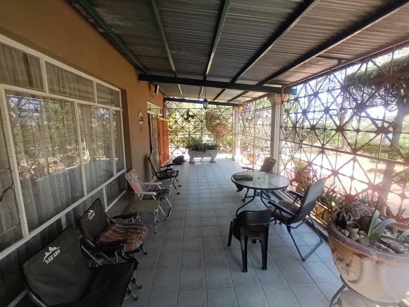 A covered outdoor patio area featuring tiled flooring, a corrugated metal roof, and decorative metal security screening, providing a functional space for outdoor relaxation.