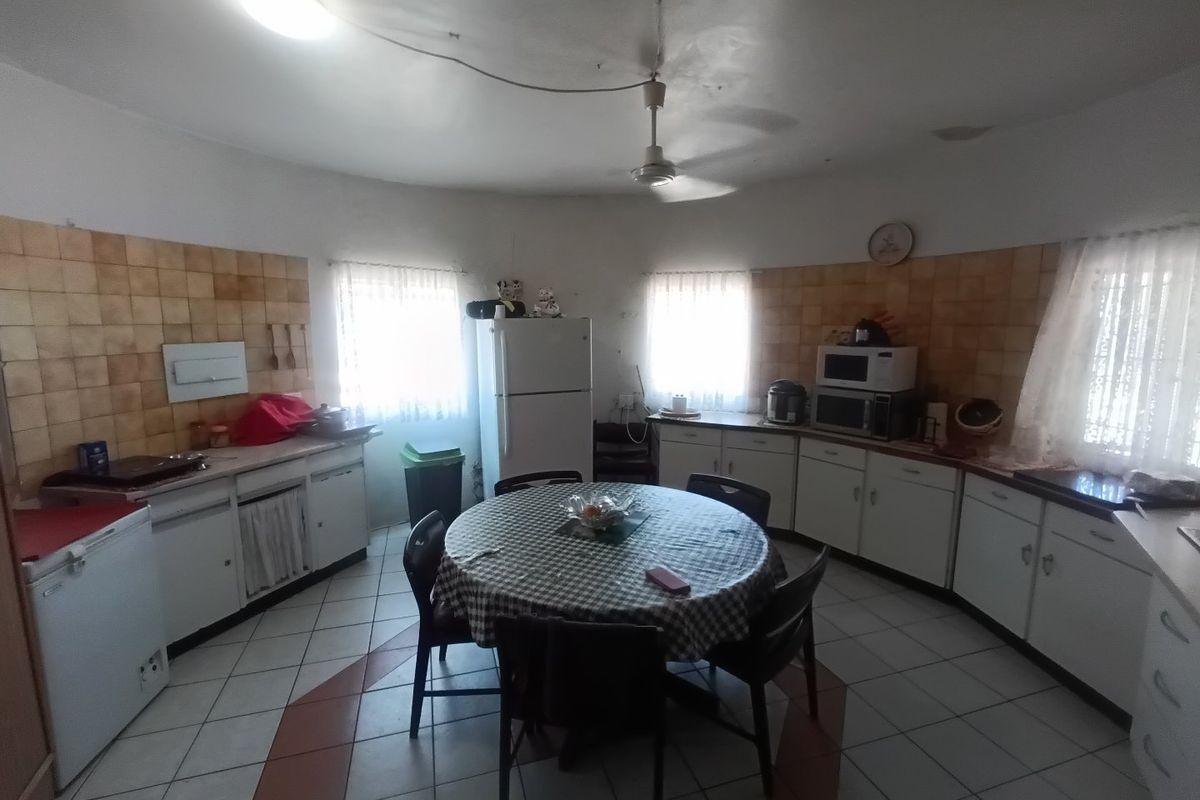 Spacious kitchen featuring dated cabinetry, tiled backsplash, and tiled flooring, offering a functional layout with ample storage and preparation space.