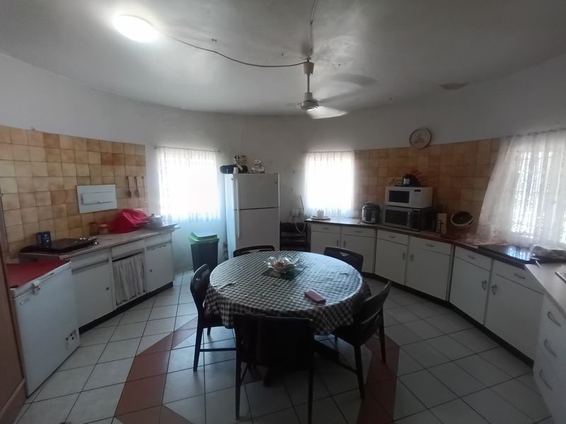 Spacious kitchen featuring dated cabinetry, tiled backsplash, and tiled flooring, offering a functional layout with ample storage and preparation space.