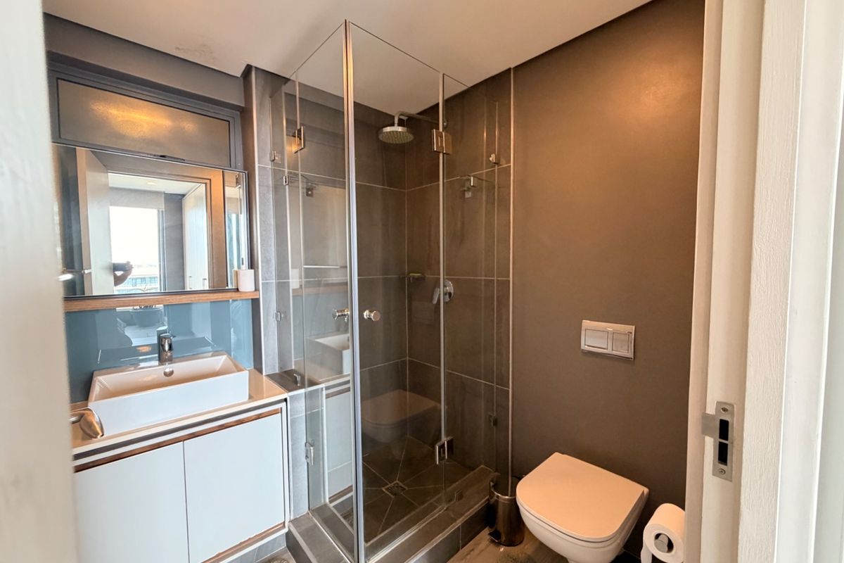 Modern bathroom featuring a glass-enclosed shower, wall-mounted toilet, and a sleek vanity with a vessel sink.