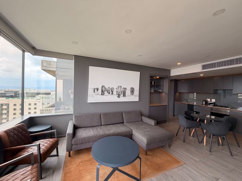 Modern open-plan living area featuring floor-to-ceiling windows, integrated kitchen cabinetry, and ducted air conditioning in a contemporary apartment setting.