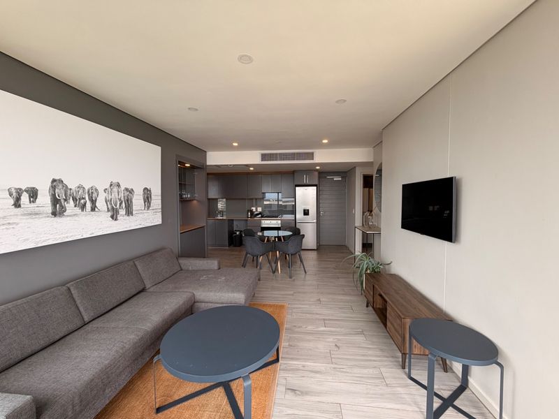 Modern open-plan living area featuring tiled flooring, recessed lighting, ducted air conditioning, and a sleek, well-appointed kitchen with integrated appliances.