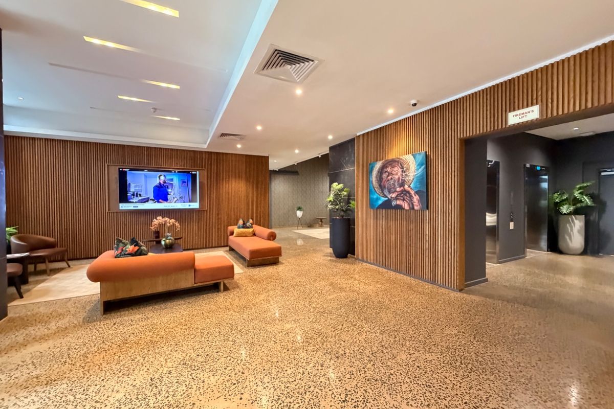 Modern apartment lobby or lounge area featuring stylish timber slat wall paneling, polished terrazzo flooring, and integrated elevator access.