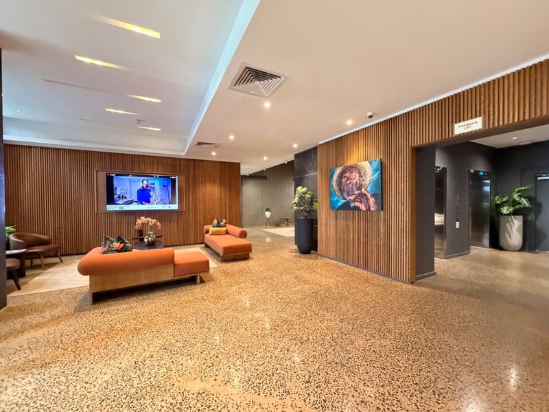 Modern apartment lobby or lounge area featuring stylish timber slat wall paneling, polished terrazzo flooring, and integrated elevator access.