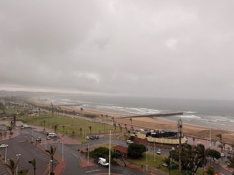 Elevated coastal view overlooking the beach, promenade, and surrounding urban infrastructure under an overcast sky.