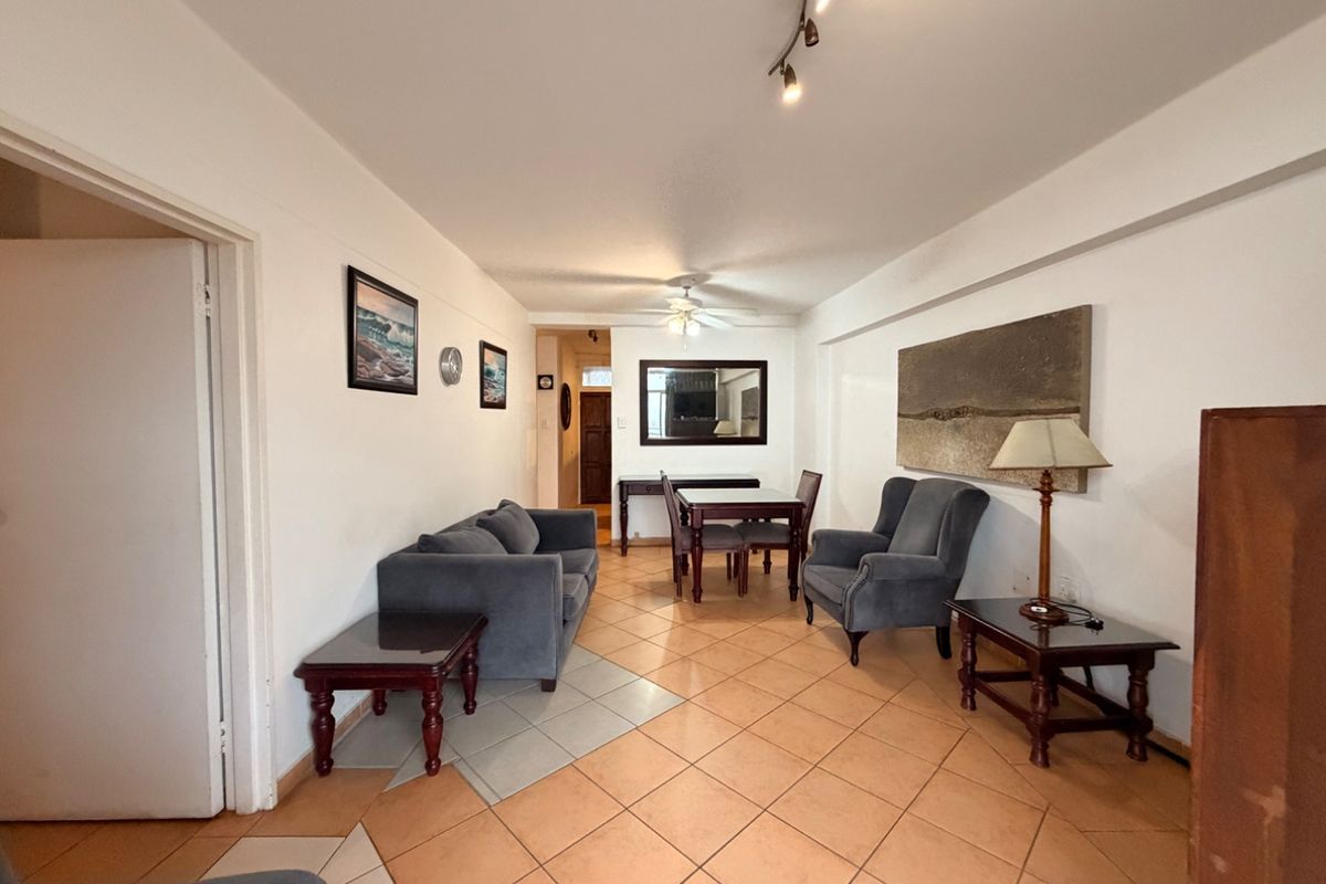 A spacious living and dining area featuring ceramic tile flooring, a ceiling fan, and track lighting, offering a functional layout for relaxation and meals.