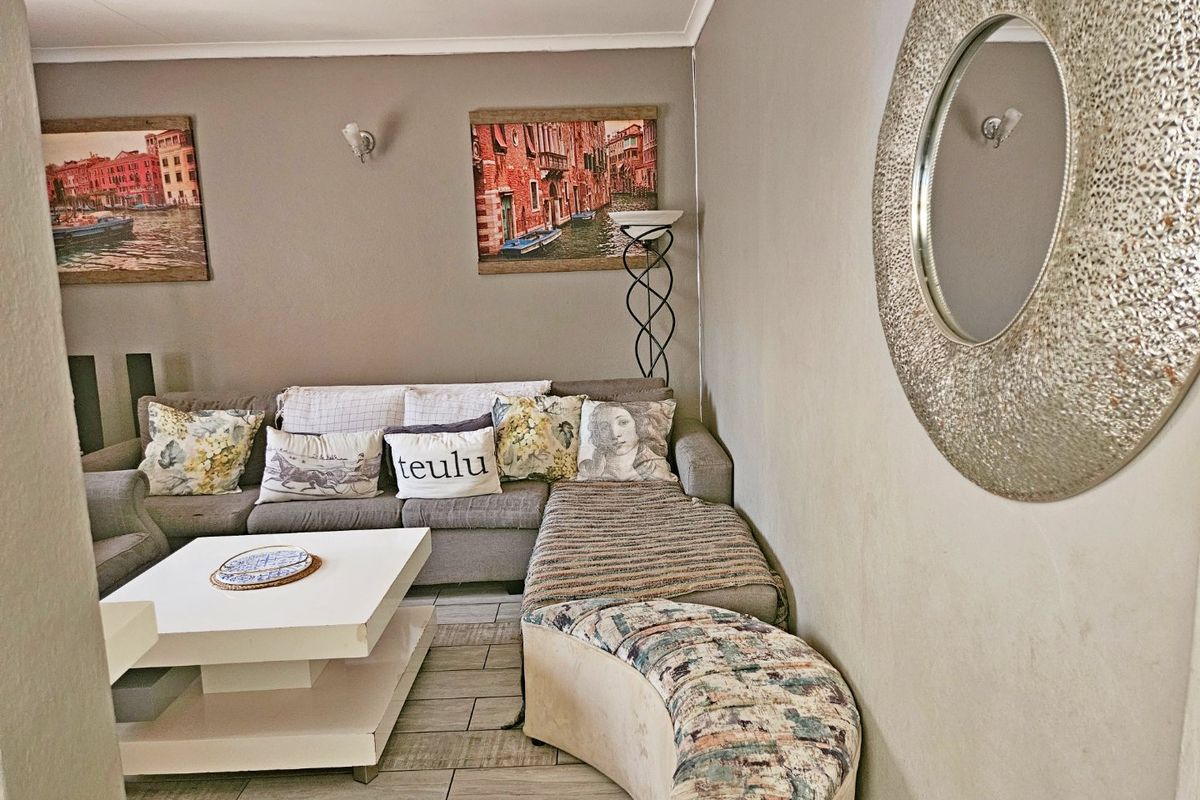 A comfortable living room featuring tiled flooring and wall-mounted lighting fixtures, providing a functional and inviting space for relaxation.