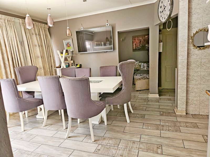 A well-maintained dining area featuring modern tiled flooring, recessed ceiling lighting, and a decorative wallpapered feature wall.