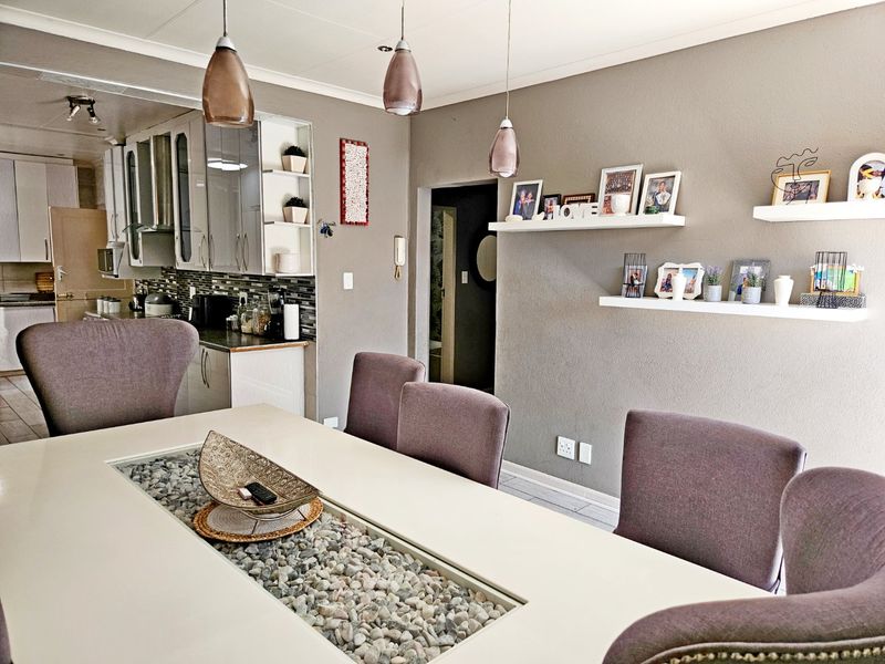 An open-plan dining and kitchen area featuring modern cabinetry, a mosaic tile backsplash, and contemporary pendant lighting.