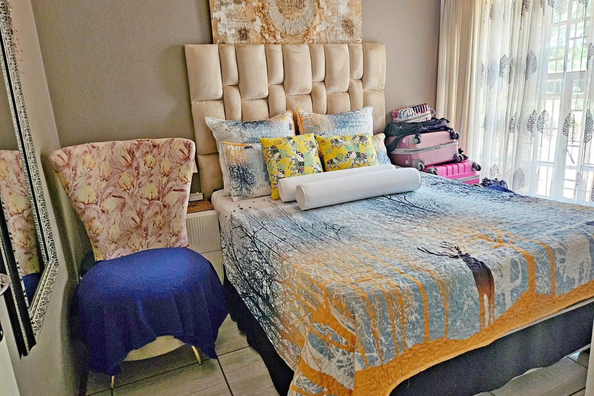 A bedroom featuring tiled flooring and large windows with curtains, providing a functional space for rest.