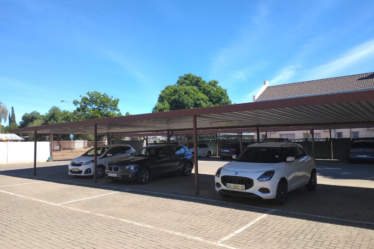 A well-maintained paved carport area providing covered parking spaces for multiple vehicles within the apartment complex.