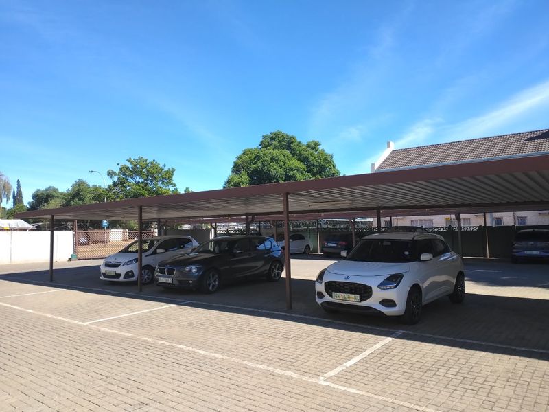A well-maintained paved carport area providing covered parking spaces for multiple vehicles within the apartment complex.