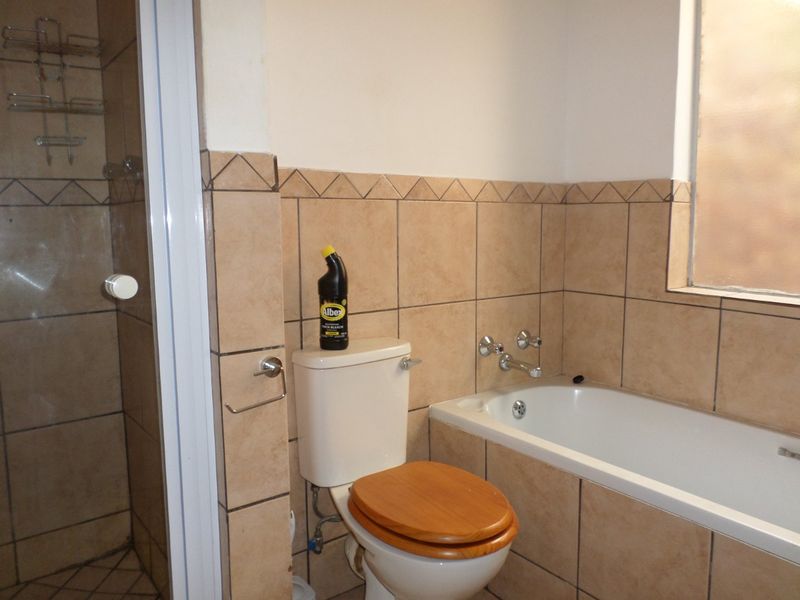 A functional bathroom featuring a bathtub, separate shower enclosure, and tiled finishes, offering potential for modernization and aesthetic updates.