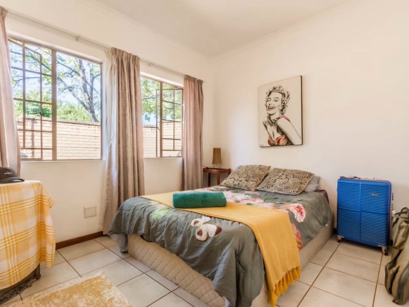 A functional bedroom featuring tiled flooring and large casement windows that provide natural light.