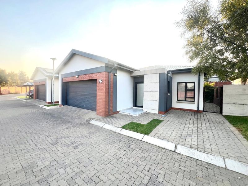 Front elevation of a modern residential property featuring a double garage, paved driveway, and clean brick and plaster exterior finishes.