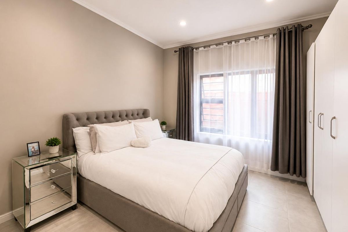 A well-maintained bedroom featuring neutral wall tones, tiled flooring, recessed lighting, and a built-in wardrobe.