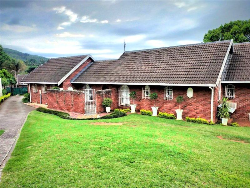 A single-story brick house featuring a tiled roof, security bars on windows, and a well-maintained front lawn with a paved driveway.
