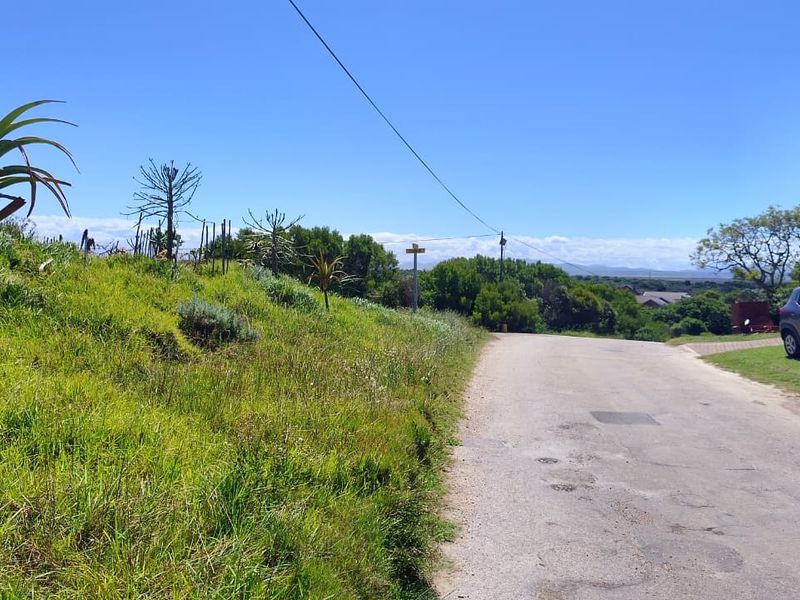 A view of the street frontage and adjacent grassy verge, showing the access road and surrounding landscape.