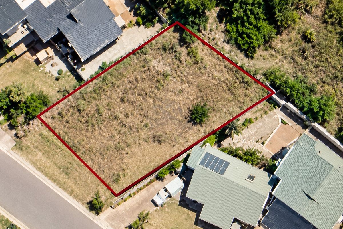 An aerial view of a vacant residential plot, clearly outlined in red, situated within an established neighborhood.
