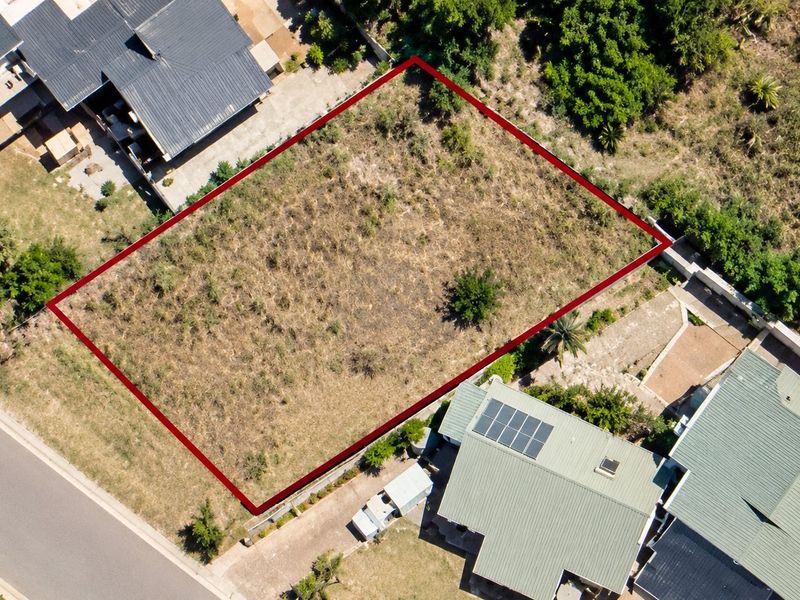 An aerial view of a vacant residential plot, clearly outlined in red, situated within an established neighborhood.