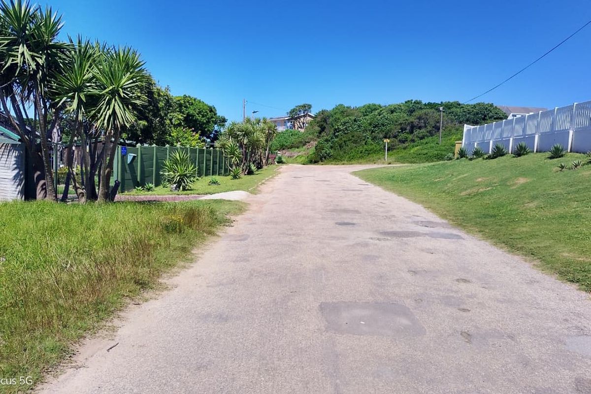 A view of the residential street access featuring an asphalt road, boundary fencing, and established landscaping along the verge.