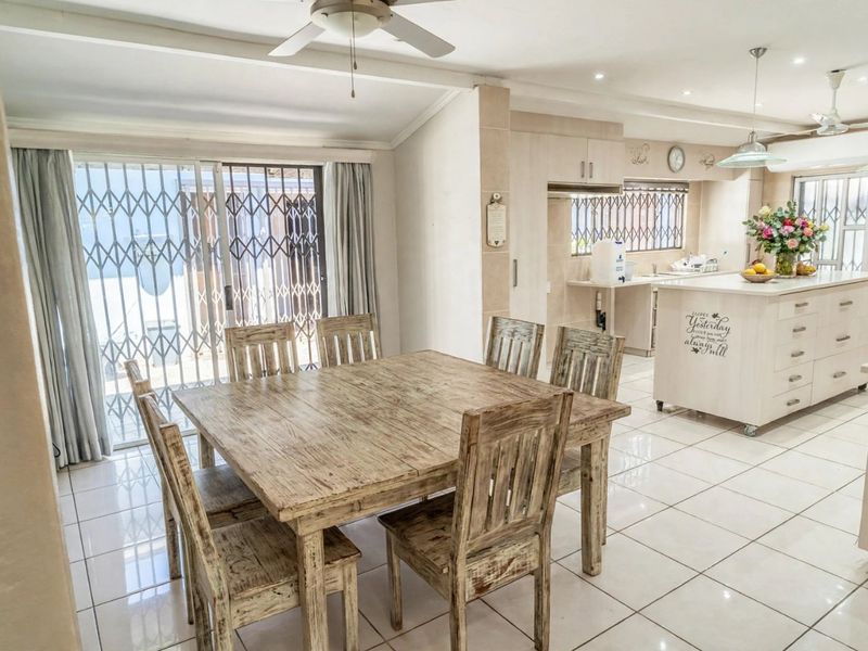 Spacious open-plan living and dining area featuring tiled floors, a central kitchen island, and sliding doors leading to the exterior.