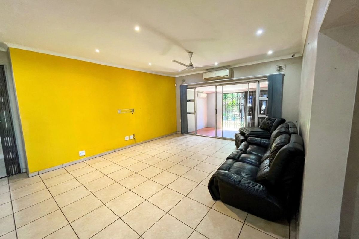 Spacious living room featuring tiled flooring, recessed lighting, a ceiling fan, and sliding glass doors that open to an outdoor patio area.