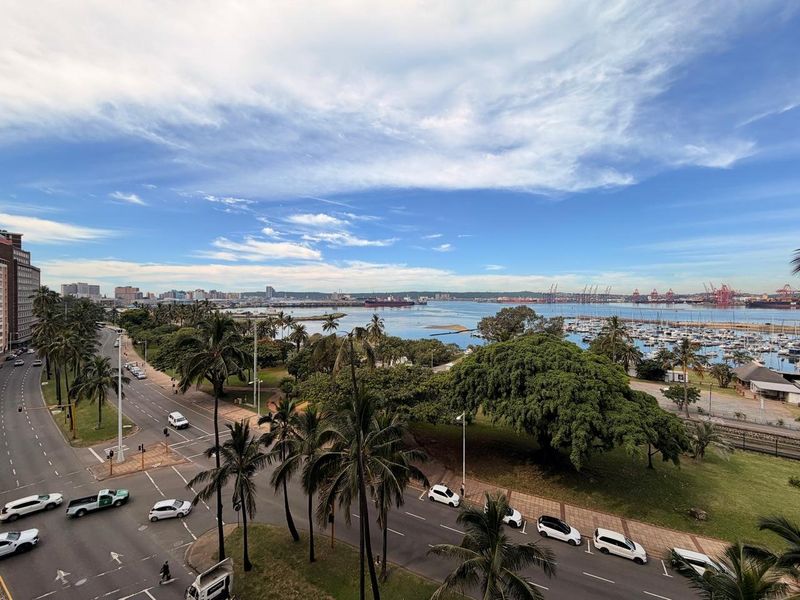 Elevated panoramic view overlooking the coastal city, harbour, marina, and surrounding urban landscape.