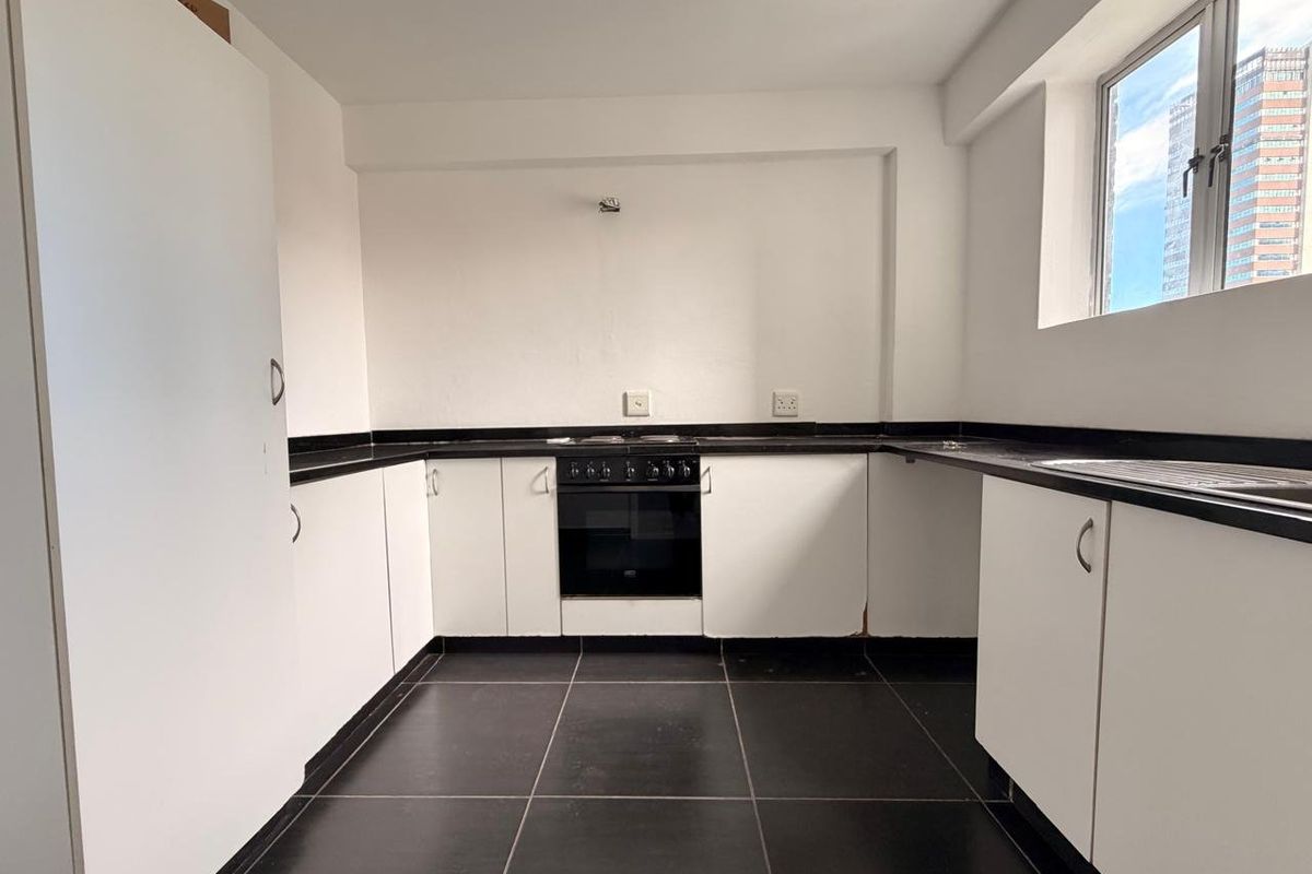 A functional kitchen featuring white cabinetry, black granite countertops, tiled flooring, and a built-in oven with hob.