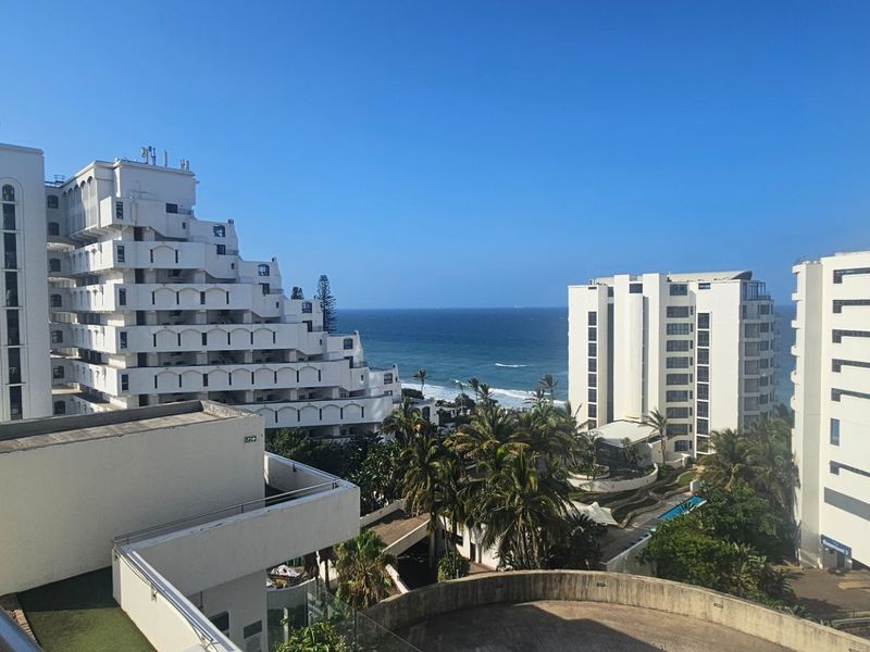 A scenic elevated view overlooking surrounding apartment buildings and the ocean coastline.